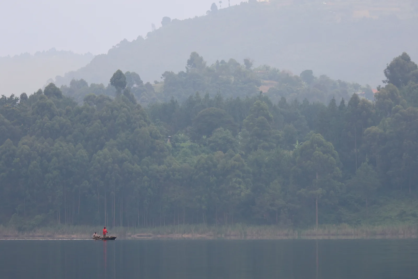 A small boat on Lake Bunyonyi beneath wooded hills, Uganda.